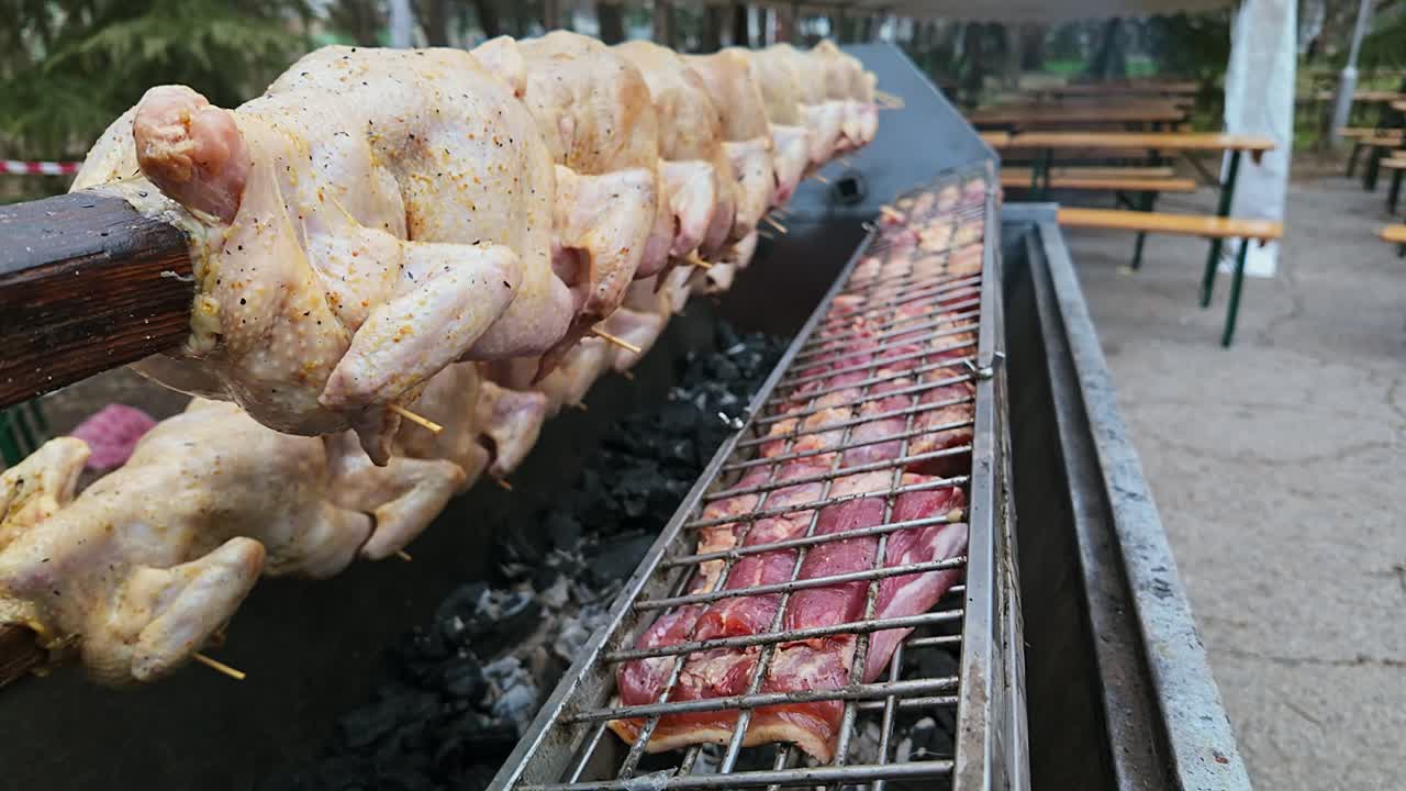 Roast Chickens and pork meats rotate on BBQ spit
