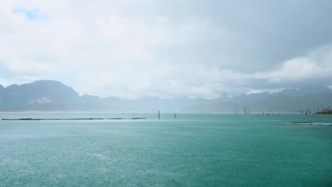 heavy rain dropping on turquoise lake with mountains on background on summer day