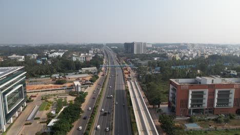 cinematic aerial footage shows a service road, fast-moving automobiles, and residential and commercial buildings on an expanding indian highway