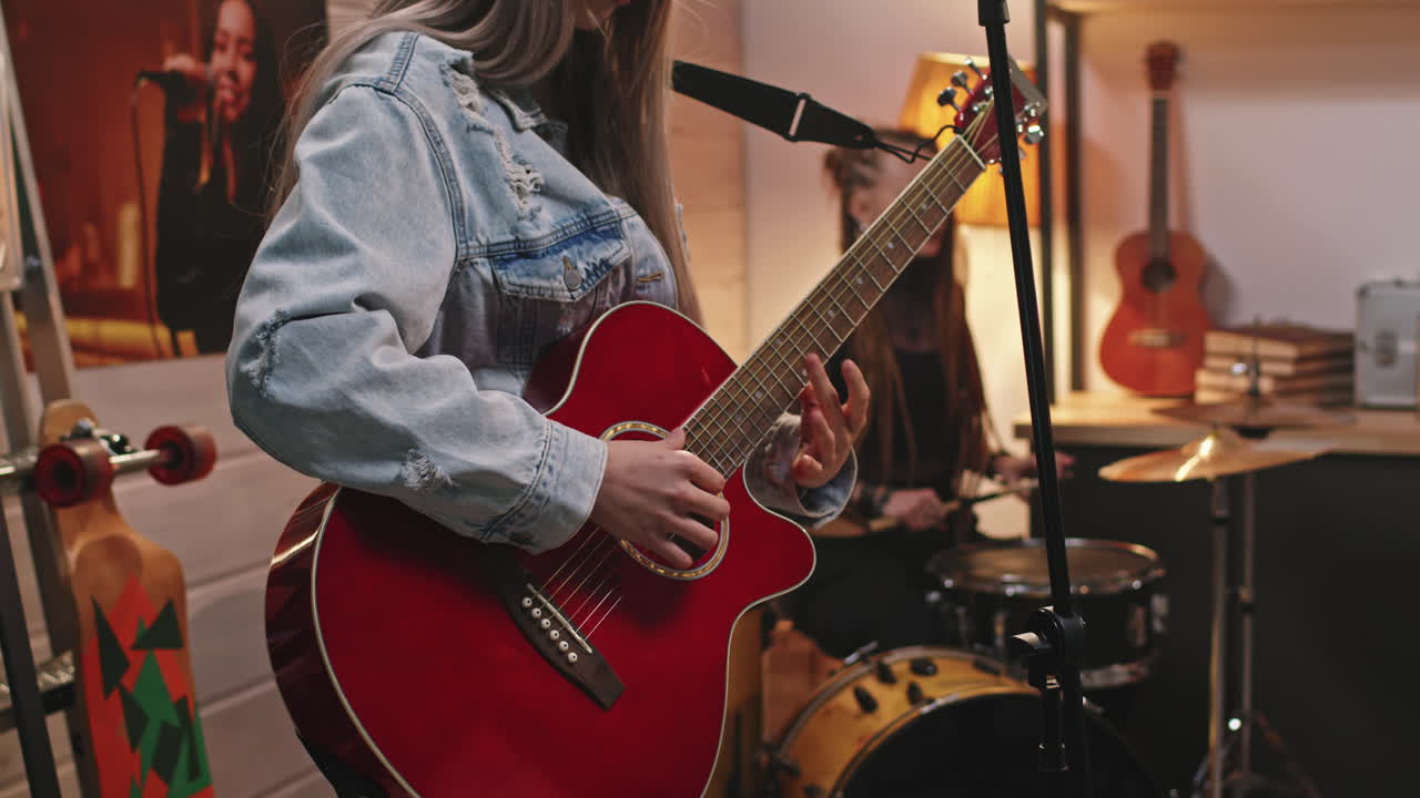 Kvindelig guitarist justerer stemmeskruer på akustisk guitar