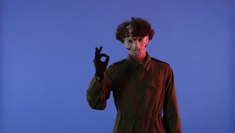 man in white mask pointing his hand in the direction and then does the like gesture on blue