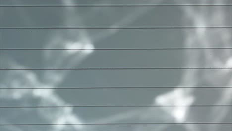 Swimming-pool-ripples-reflect-on-wooden-ceiling-of-pool-house-on-a-beautiful-sunny-day