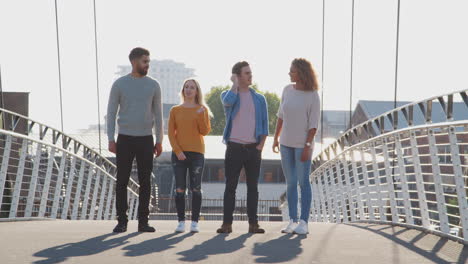 group of young friends standing on city bridge together