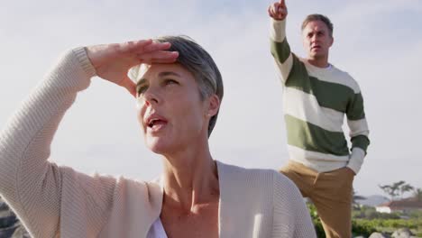 caucasian couple enjoying free time by sea on sunny day looking away