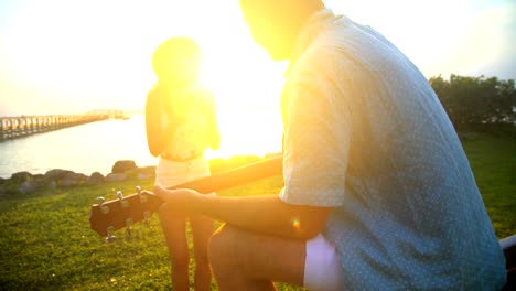 multi ethnic couple playing guitar taking sunset picture