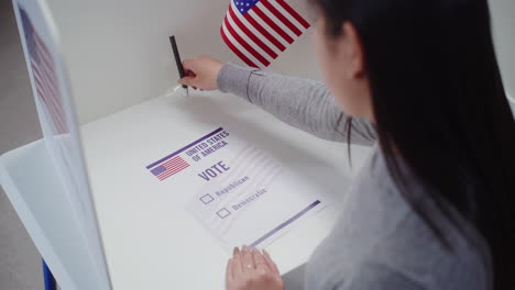 asian female voter votes for republican party in paper ballot asian female voter comes to voting booth at polling station makes choice and votes for republican party in paper ballot american citizen during national election day in the united states civic duty