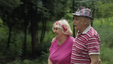 Senior-caucasian-couple-walking-in-park-embracing.-Elderly-man-walks-with-woman.-Husband,-wife