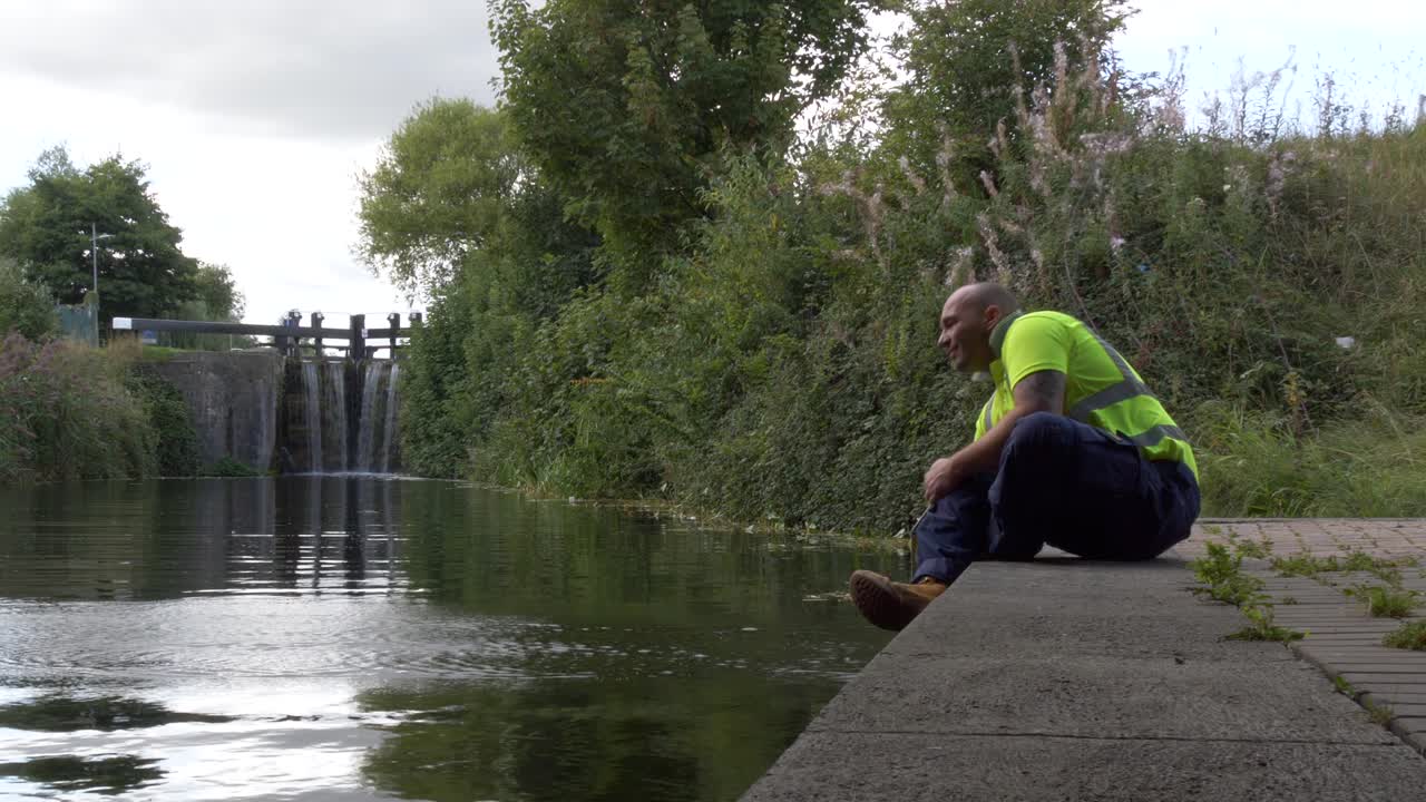 아일랜드의 더블린 운하에서 물을 튀기며 직장에서 휴식을 취하는 창고 남성 노동자