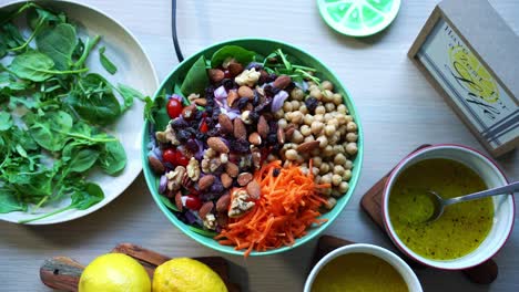 aerial top view chick peas assorted nuts salad on a rotating platform carrots tomatoes salad dressing on the side