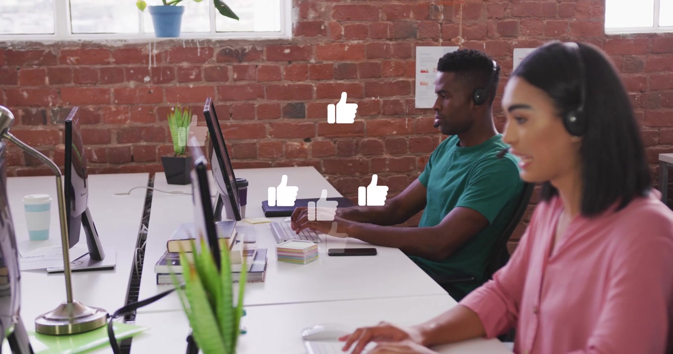 Animation of like icons against diverse man and woman wearing phone headset working at office