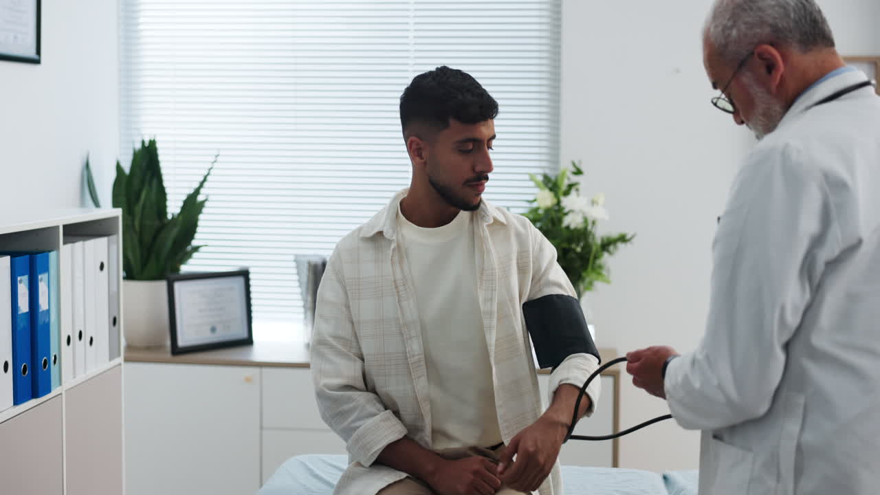 Doctor Measuring Blood Pressure of Young Male Patient in Clinic