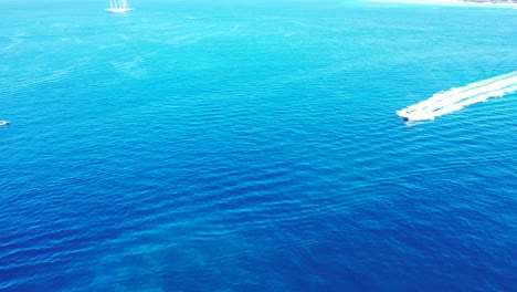 Barco-Navegando-A-Través-De-La-Superficie-Azul-Del-Mar,-Rastreando-Aguas-Tranquilas-Y-Claras-Por-Olas-Blancas,-Copiando-Espacio-Con-Textura-Marina