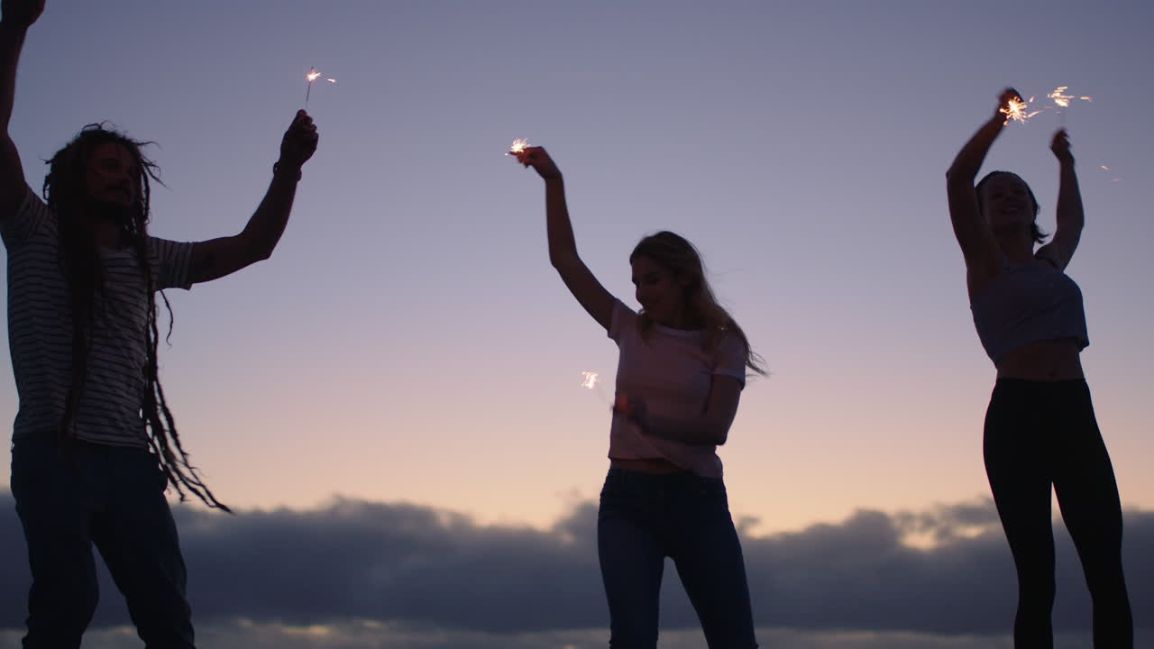 즐거운 새해를 축하하며 폭죽을 흔들며 춤을 추는 친구들