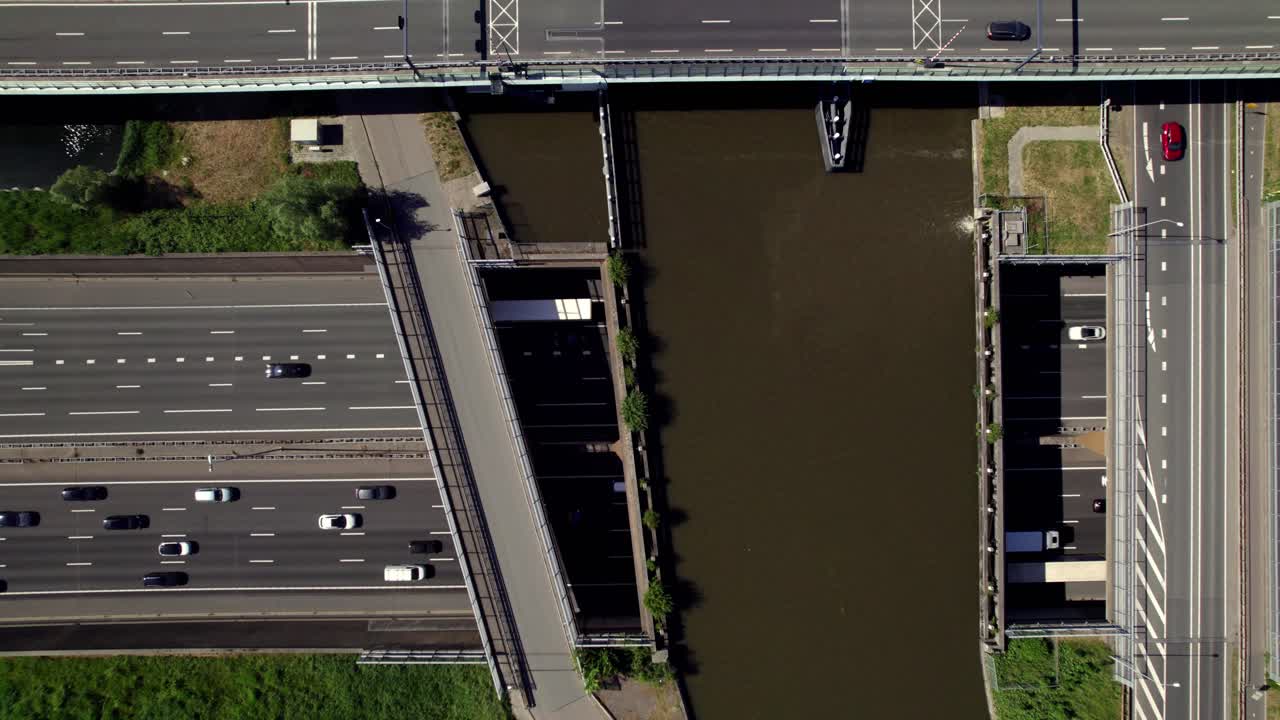 Aerial iInland shipping waterway infrastructure over and under freeway intersection with commute traffic passing by near Gouda