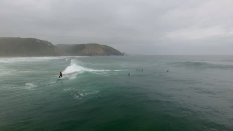 cinemática de acción aérea sobrevolando a los surfistas surfeando en coffee bay en sudáfrica
