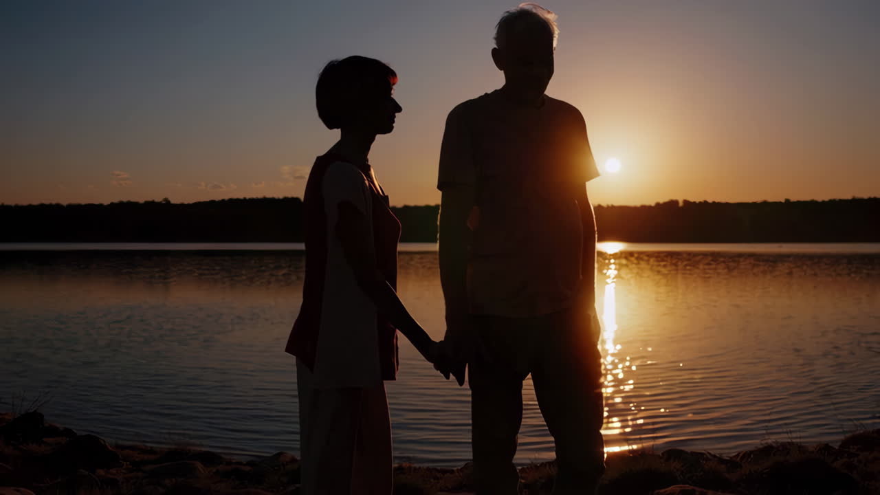 호수 에서 해가 지는 동안 손을 잡고 있는 부부