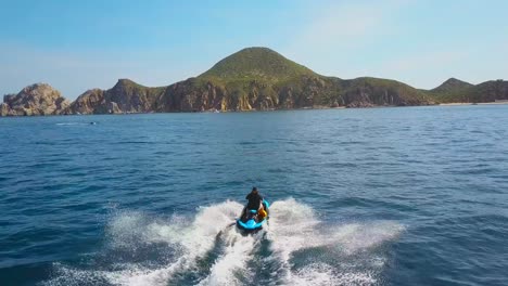 Toma-Aérea-De-Un-Hombre-Disfrutando-Del-Verano-En-Una-Moto-De-Agua-En-Medio-Del-Mar-Divirtiéndose-Corriendo-Solo-Y-Aislado