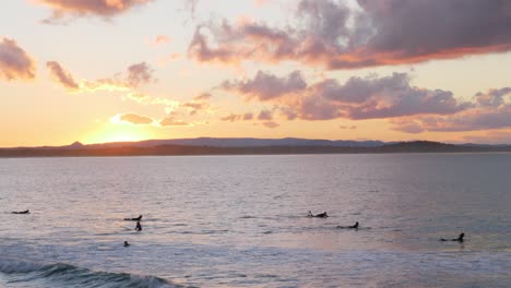 group of surfers enjoys the ocean waves with a view of sunset at the beach in noosa national park