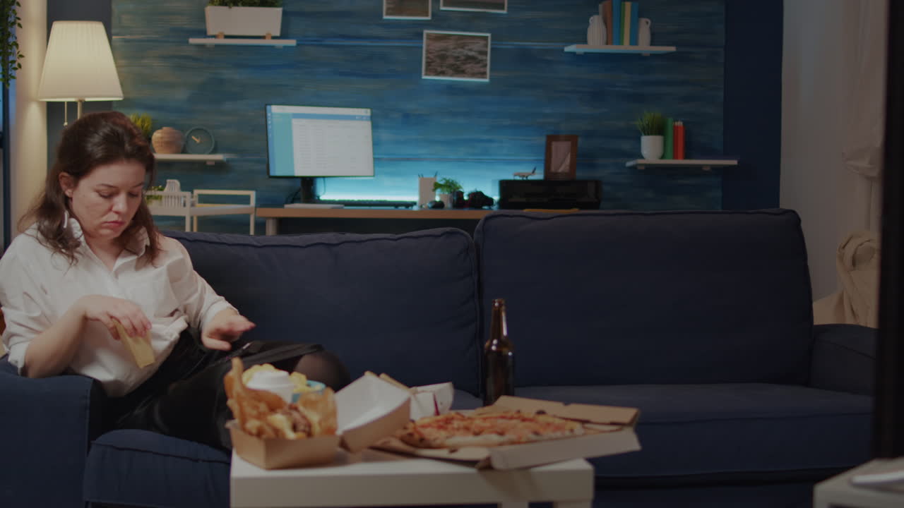 Woman relaxing on couch with takeaway food at home