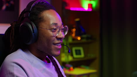 man in headphones smiling while playing video games