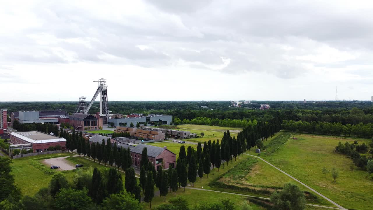 Ogromna wieża i kompleks przemysłowy otoczone lasem, widok z lotu ptaka.