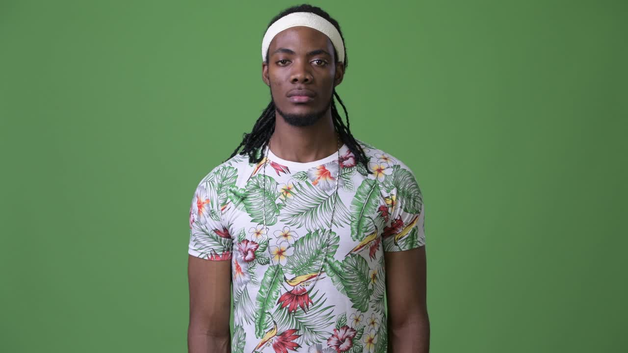 joven hombre africano guapo con dreadlocks contra un fondo verde