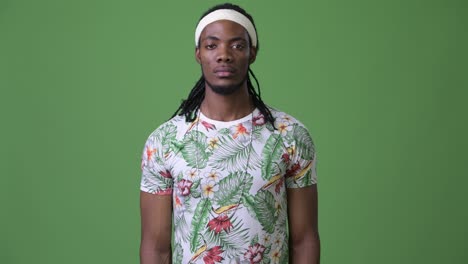 young handsome african man with dreadlocks against green background
