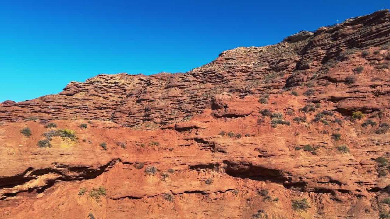 Pingshan Lake Grand Canyon, Zhangye, provincia di Gansu, Cina - Stratificazioni di arenaria rossa si ergono su un paesaggio arido sotto un cielo blu vivido e terso - Ripresa panoramica a destra