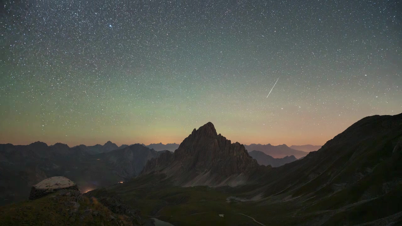 Stars fade into soft dawn light as a rugged central peak transitions from night to full daylight in a smooth timelapse.