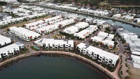 Drone-aerial-over-town-houses-by-the-river-with-mountains