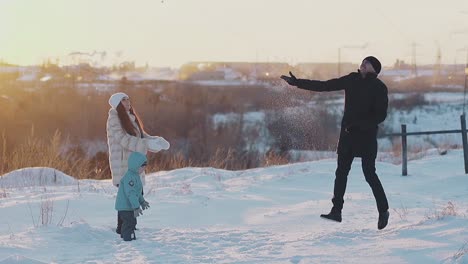 man in black sheepskin coat throws up white snow up jumping