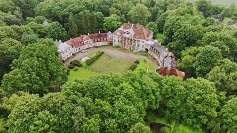 approaching aerial of kaucminde manor in rundāle, latvia under cloudy grey sky