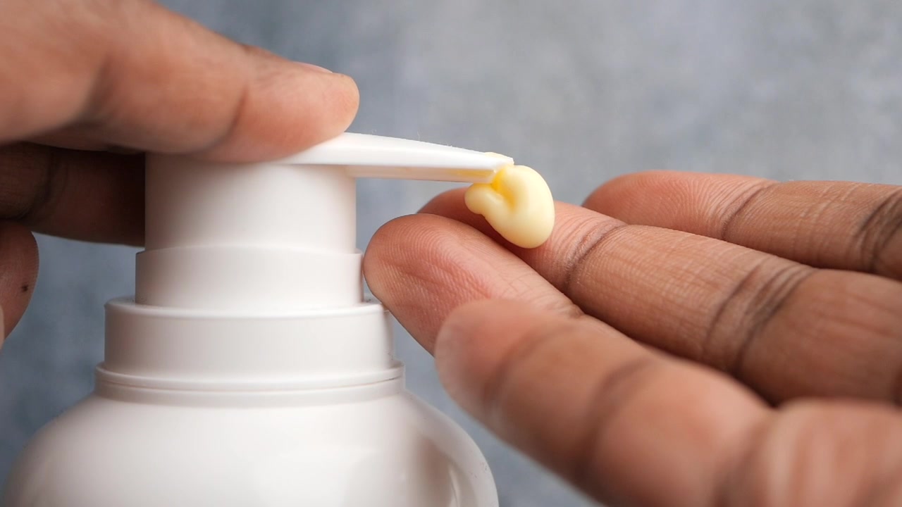 白いポンプボトルからクリームを出す人