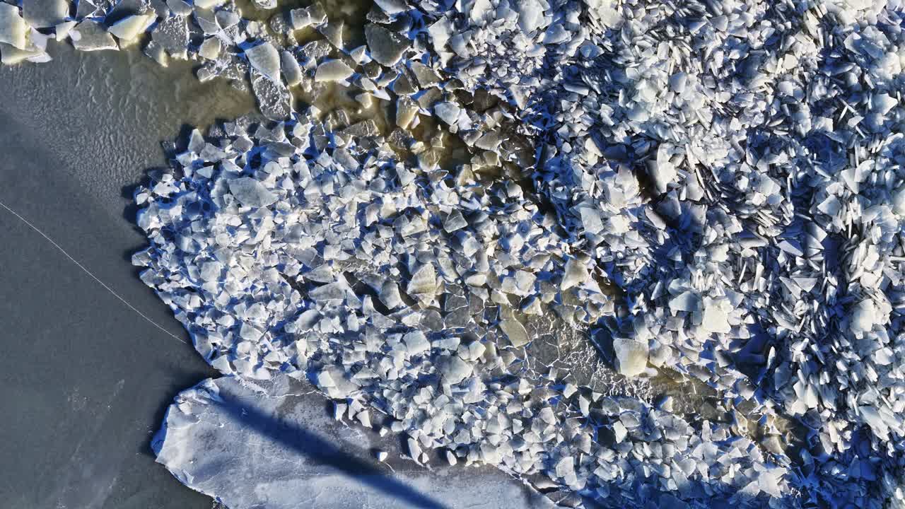 Lastre di ghiaccio spezzate su acqua ghiacciata, che creano intricati disegni freddi e forme astratte