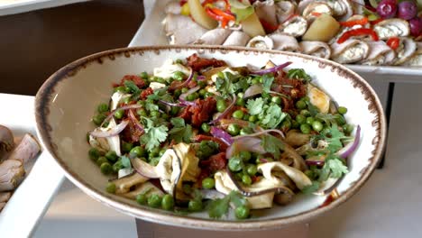 platter with a salad consisting of eggplant, peas, onion, sun-dried tomatoes, and herbs