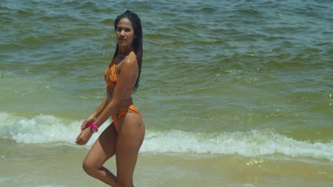 on a sun-kissed caribbean beach, a bikini-clad young woman with curly hair revels in the joyous embrace of the waves