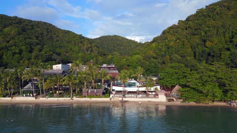 perfect aerial top view flight
beach village huts resort, tropical bungalows on mountainous island thailand 2022