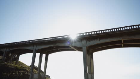 looking up at an old coastal california bridge with the sun shining through the beams