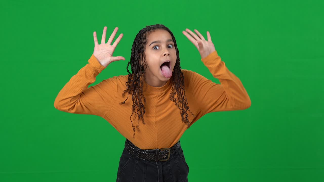 Laughing African American teen girl grimacing gesturing on green screen mocking. Portrait of adolescent bully sneering on chromakey background pointing at camera. Adolescence concept.