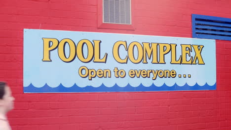 girl walks past a swimming pool sign