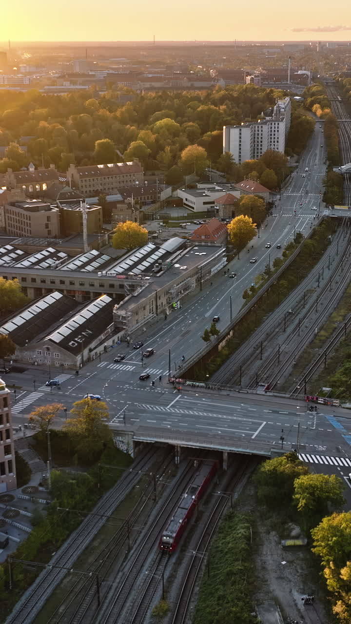 Aerial drone view of a train moving on the tracks near Vesterbro district in Copenhagen, Denmark at sunset. Vertical
