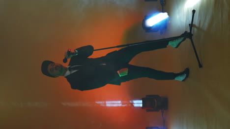 video vertical. cantante divertido incendiario con ropa elegante bailando y cantando con un micrófono de color neón. saltar y moverse vigorosamente. cantante pop