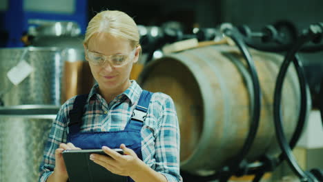 Lab-Technician-With-Protective-Glasses-Works-With-A-Tablet-In-The-Workshop-On-The-Background-Of-Wine