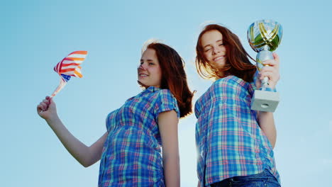 two teenage twins girls with a winner's cup and an american flag 1