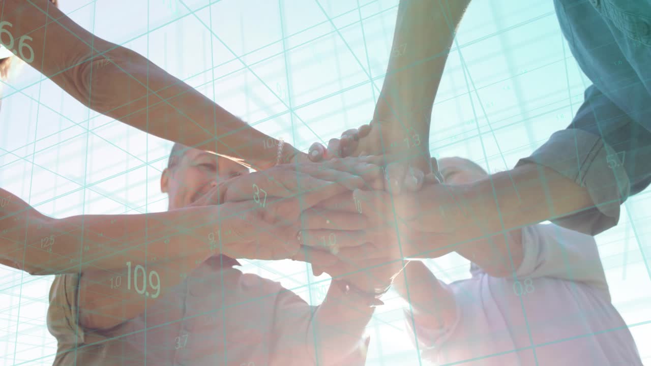 Camera below capturing four colleagues leaning stacking hands marking business win numeric overlay
