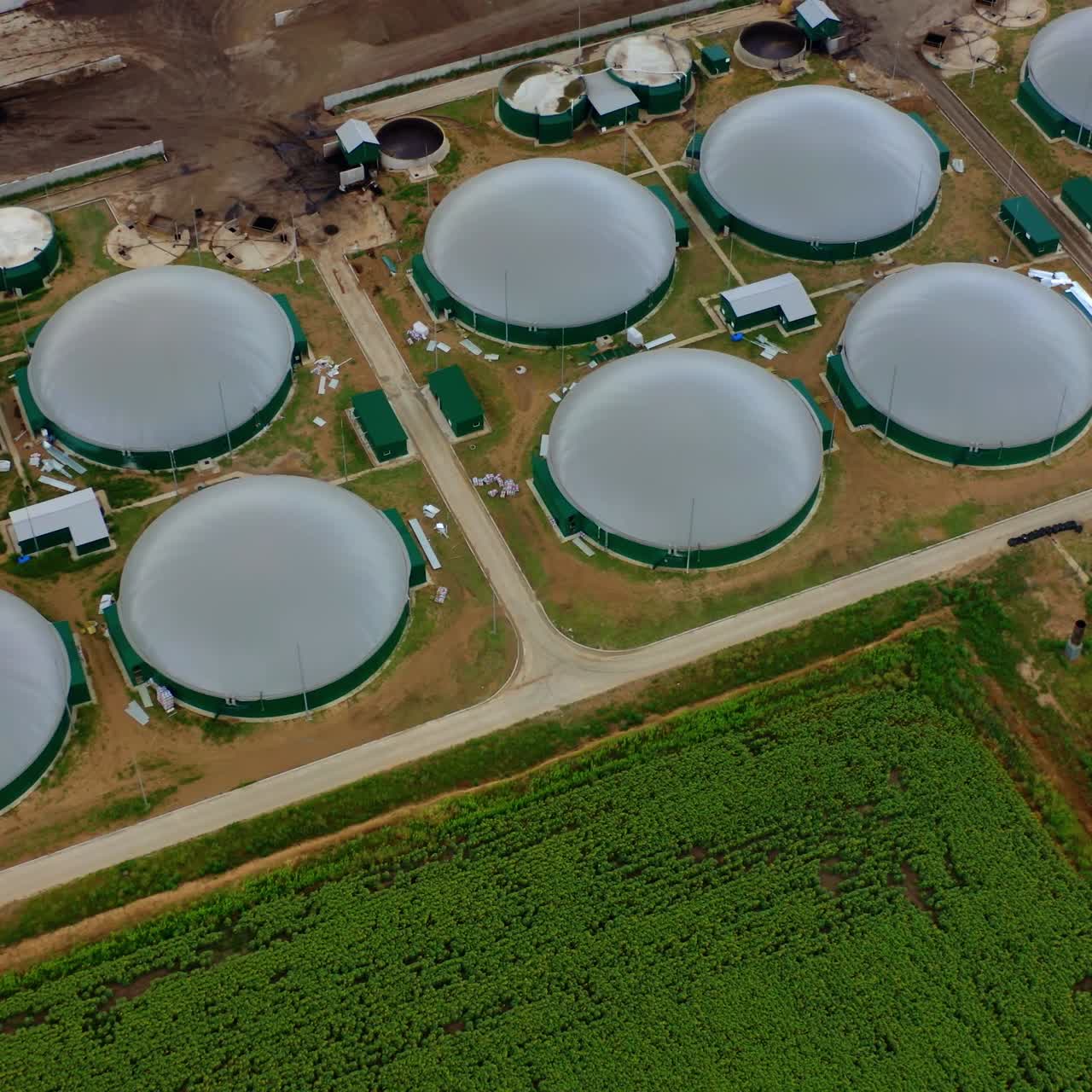 Production of biogas. Factory production of methane-containing gas. Modern agricultural plant on field. Aerial view.