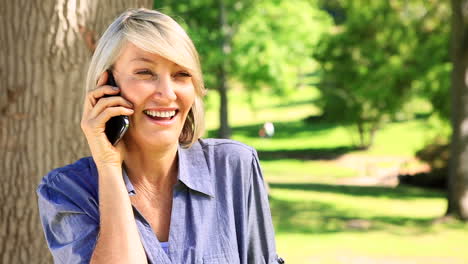 Mujer-Feliz-Charlando-Por-Su-Teléfono-En-El-Parque