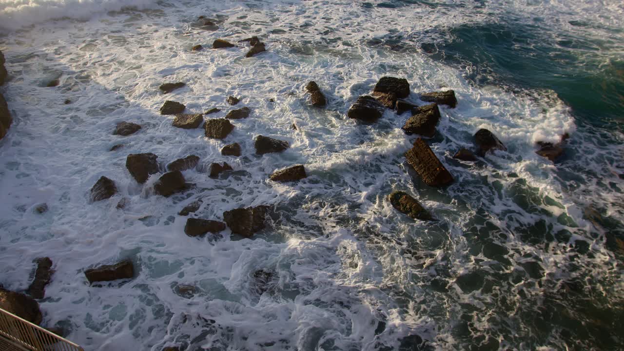 바람에 따라 움직이는 색 거품과 함께 파동의 넓은 느린 동작 정적, 시라큐스, 시칠리아 (이탈리아) 에서 작은 바위로 둘러싸여 있습니다.