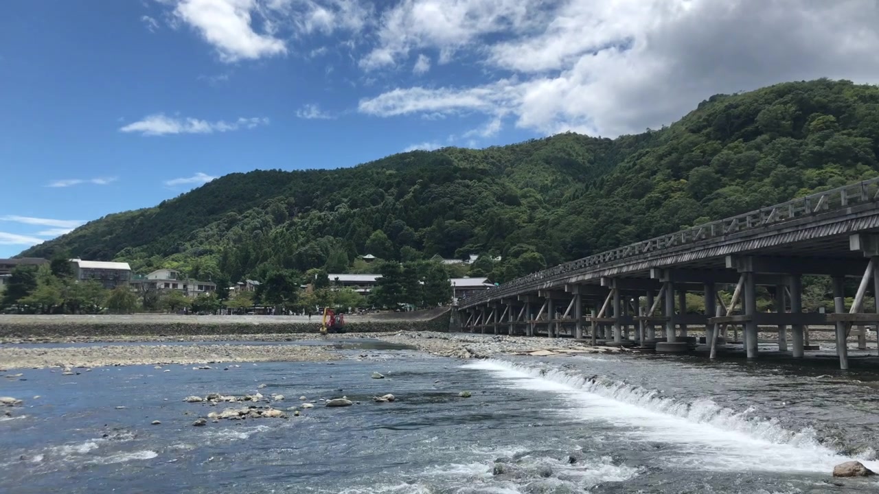 Ghi lại một cảnh thanh bình từ phía hạ lưu cầu Togetsukyo ở Kyoto, lia máy chậm sang phải. Trải nghiệm một khung cảnh yên bình khi cây cầu dần hiện ra trong khung hình trên nền trời xanh trong, rực rỡ.