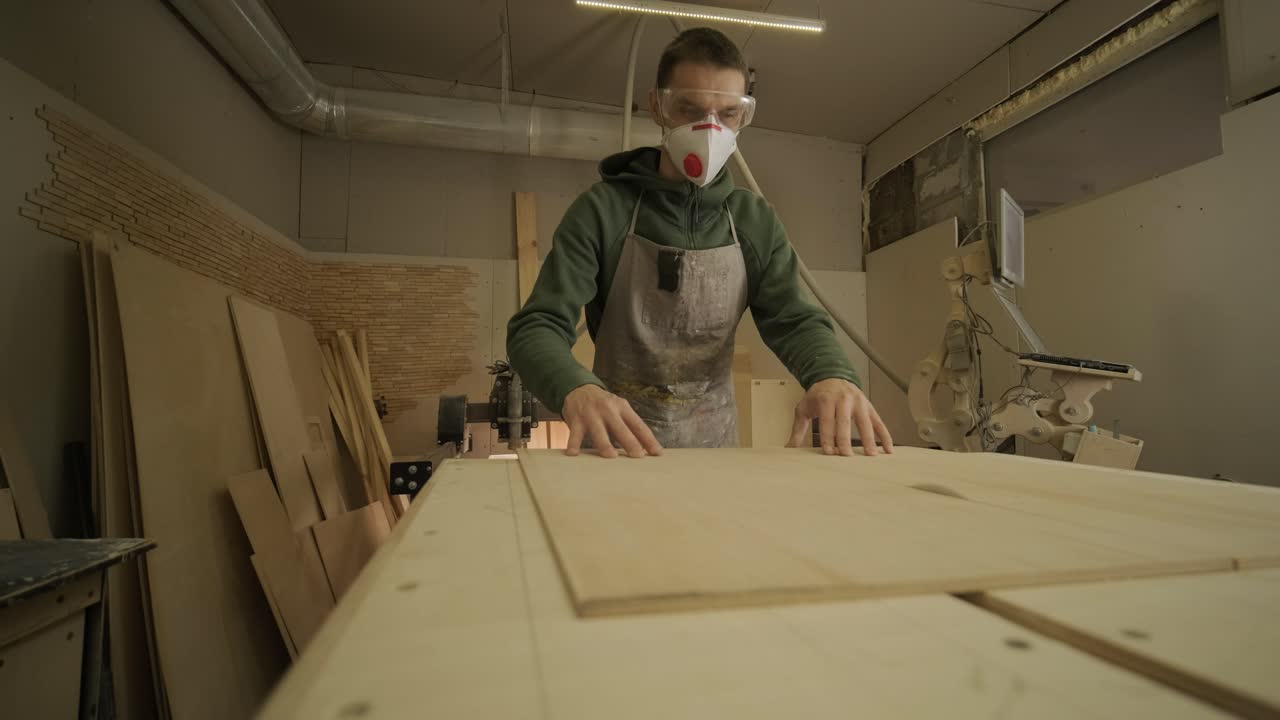 el carpintero corta tabla de madera, panel de contrachapado, madera en bruto en el taller utilizando una máquina de corte